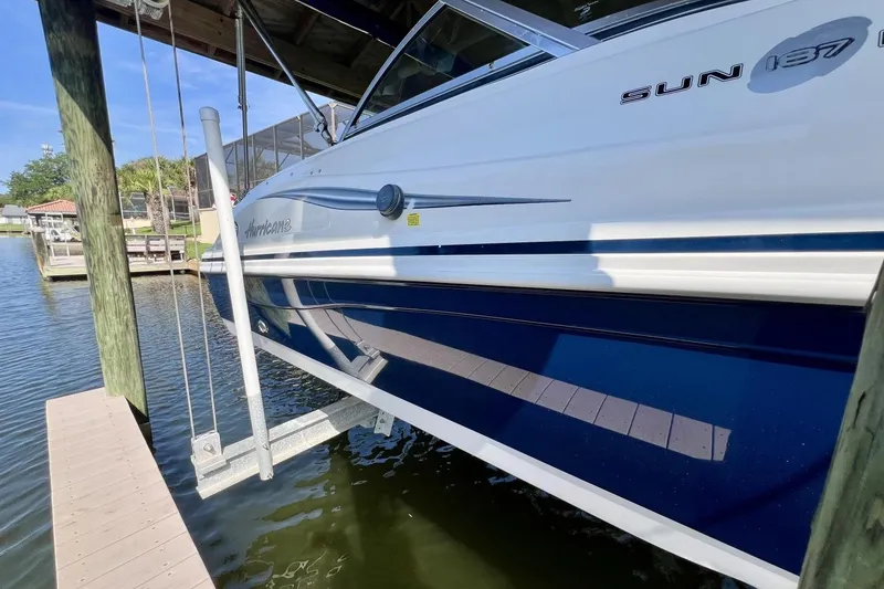 Slide: The Image of 2013 Hurricane SunDeck 187 OB boat docked on a lift by the water. - 80