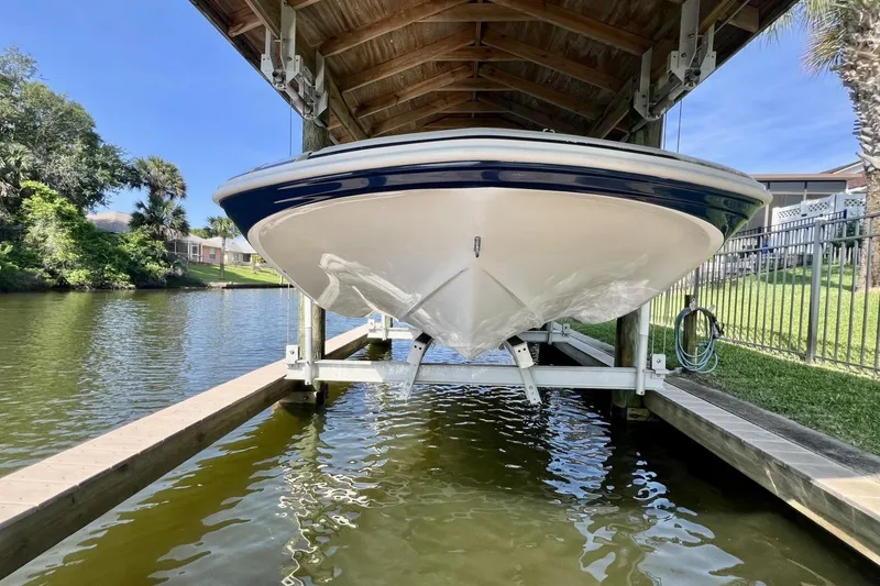 Slide: The Image of 2013 Hurricane SunDeck 187 OB boat docked under a wooden canopy by a riverside. - 83