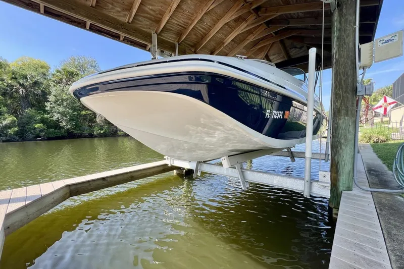 Slide: The Image of 2013 Hurricane SunDeck 187 OB boat on lift under wooden canopy by riverside. - 84