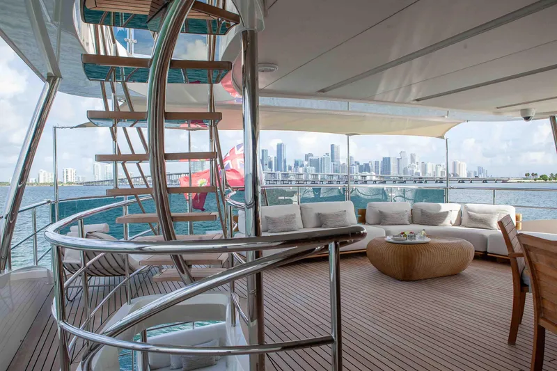 Slide: The Image of Luxurious Benetti Classic Supreme 132 yacht deck with city skyline view, featuring elegant seating and spiral staircase. - 14