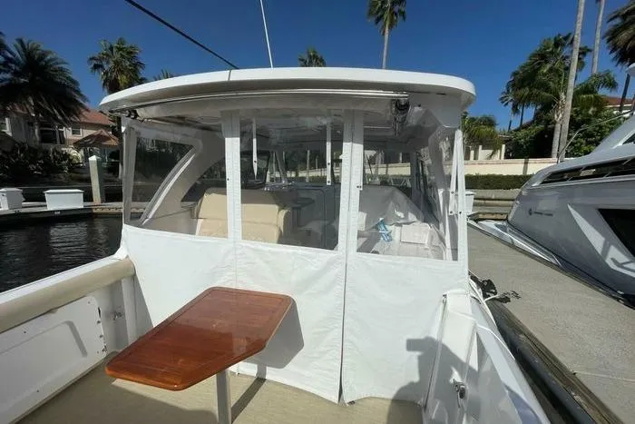 Slide: The Image of 2022 Southport 33 DC boat with enclosed cockpit and wooden table, docked under clear skies. - 6