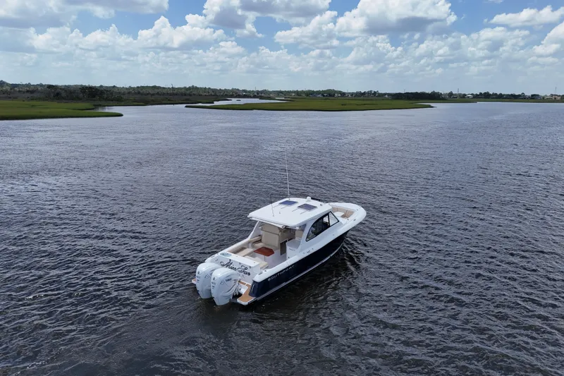 Slide: The Image of 2022 Southport 33 DC boat cruising on a serene lake under a cloudy sky. - 28