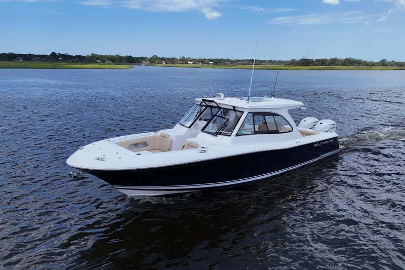 Slide: The Image of 2022 Southport 33 DC boat cruising on a calm river under a clear blue sky. - 9