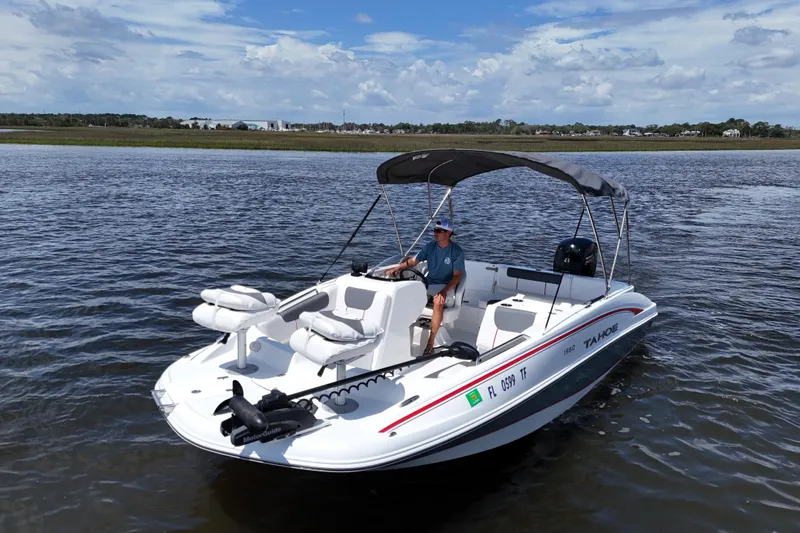 The Image of Man steering 2022 Tahoe 1950 boat on calm water under blue sky. - 0