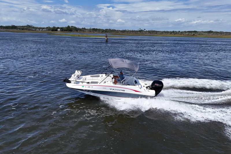 Slide: The Image of A 2022 Tahoe 1950 boat cruising on a scenic waterway under a clear blue sky. - 17