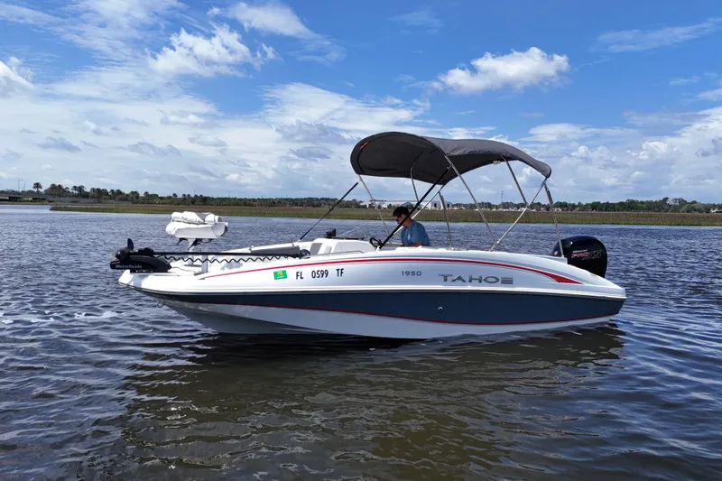 Slide: The Image of A 2022 Tahoe 1950 boat cruising on a calm lake under a clear blue sky. - 19
