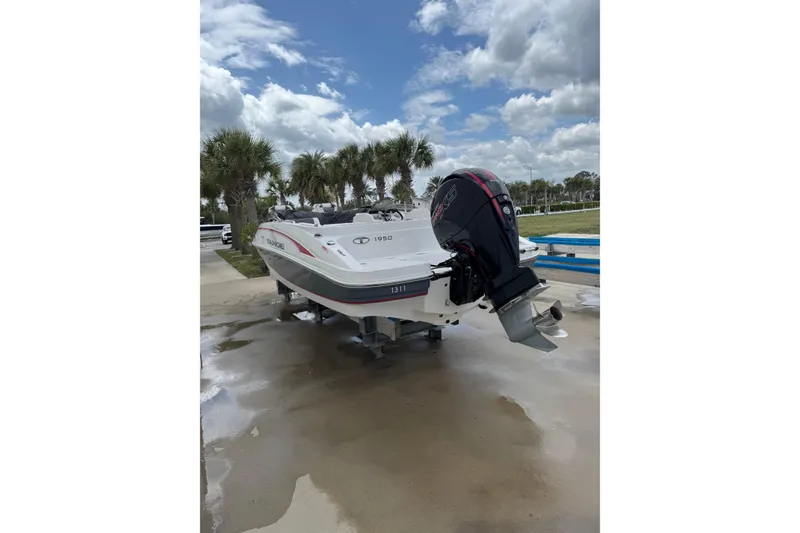 Slide: The Image of 2022 Tahoe 1950 boat with outboard motor, parked on a wet surface under a cloudy sky. - 26
