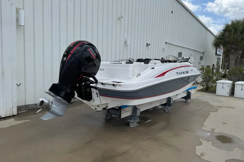 Slide: The Image of 2022 Tahoe 1950 boat with outboard motor, displayed outdoors on a stand. - 28