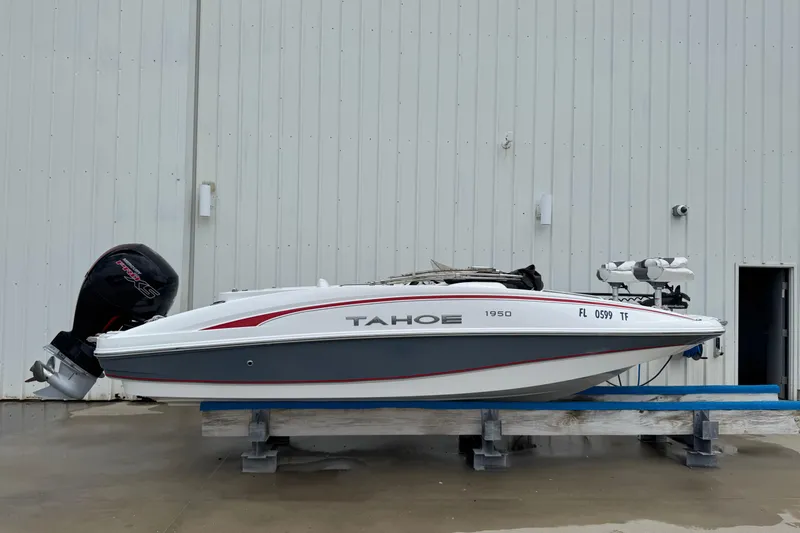 Slide: The Image of 2022 Tahoe 1950 boat on stand, white and gray with red accents, outboard motor attached. - 31