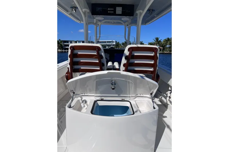 Slide: The Image of 2021 Jupiter 34 boat interior with open storage compartment, wooden seats, and ocean view. - 10