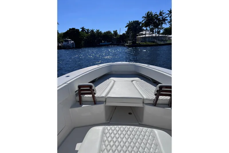 Slide: The Image of Bow view of 2021 Jupiter 34 boat on a sunny day, surrounded by water and palm trees. - 8