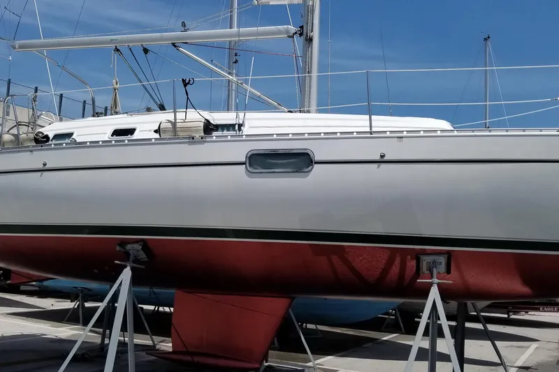 Slide: The Image of 1997 Beneteau Oceanis 321 sailboat on stands, white hull, red bottom, marina setting. - 24