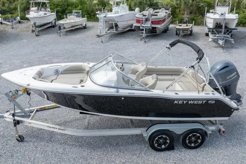 Slide: The Image of 2022 Key West 203 DFS boat on trailer, surrounded by other boats in a gravel lot. - 12