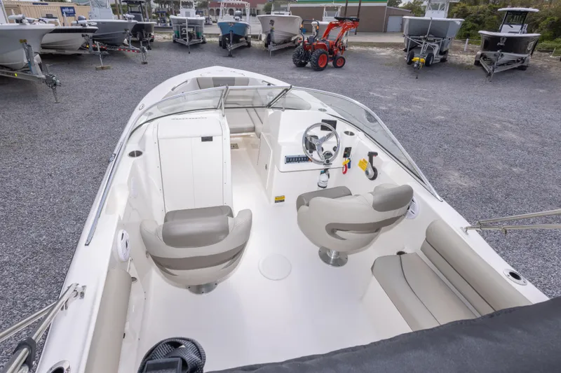 Slide: The Image of 2022 Key West 203 DFS boat interior with steering wheel and seating in a gravel lot. - 19