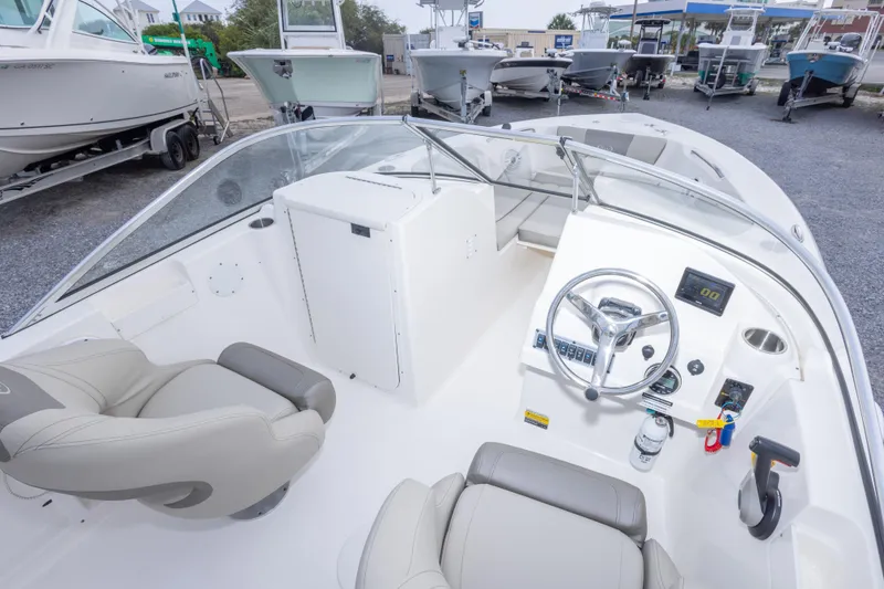 Slide: The Image of 2022 Key West 203 DFS boat interior with steering wheel and seating, displayed in a showroom. - 24