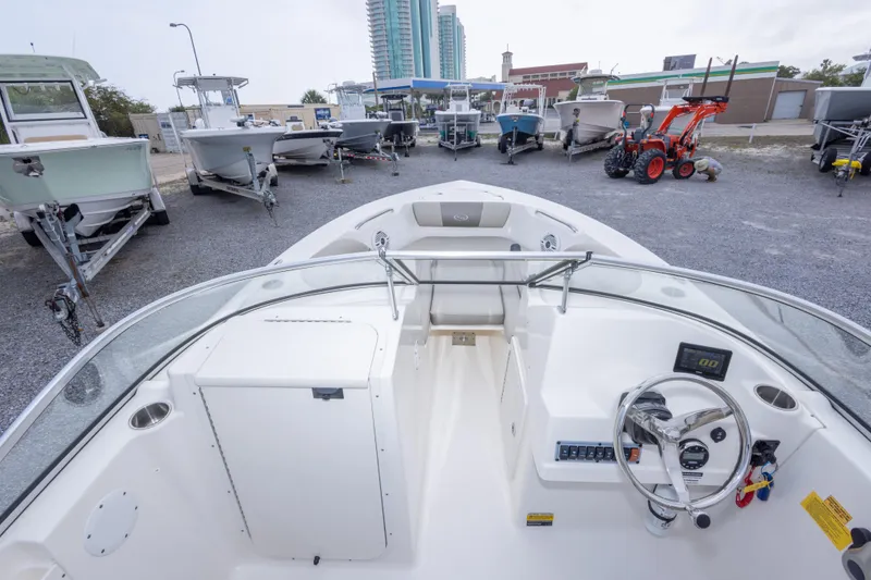 Slide: The Image of 2022 Key West 203 DFS boat interior with steering wheel, dashboard, and seating, parked among other boats. - 32