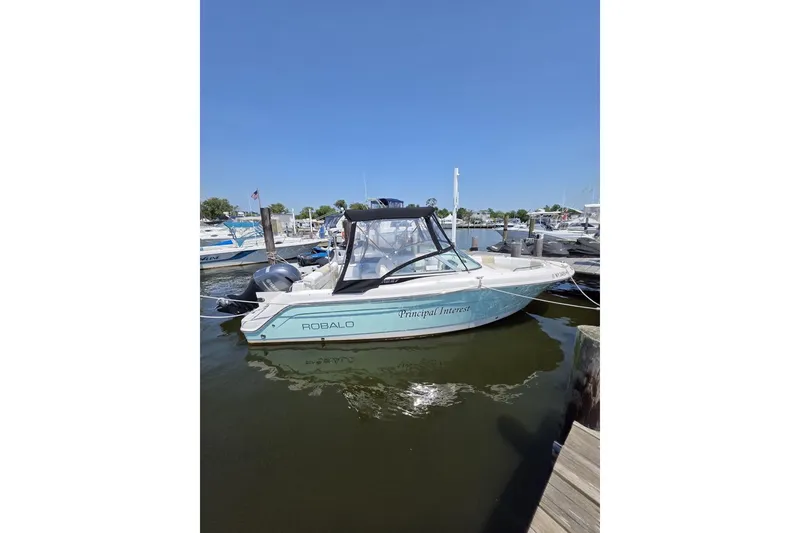 The Image of 2018 Robalo R227 Dual Console boat docked in a marina under clear blue skies. - 0