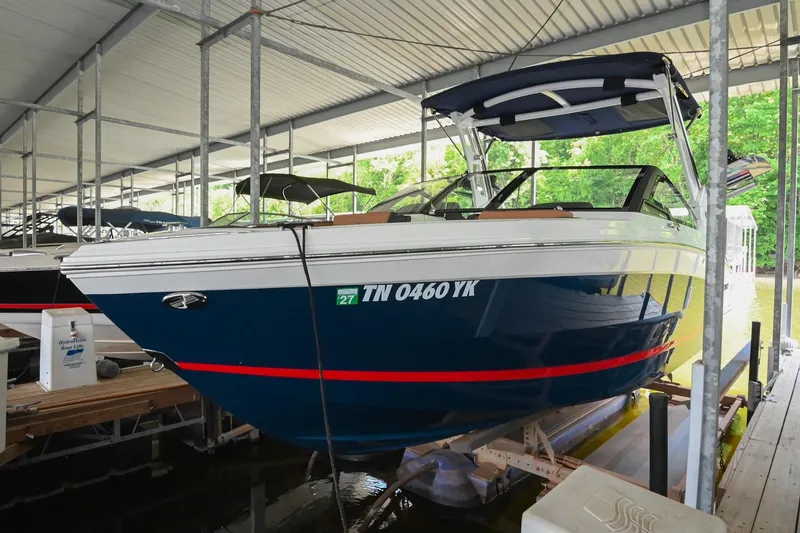 Slide: The Image of 2022 Cobalt R6 Surf boat docked in a covered marina, featuring sleek blue and white design. - 8
