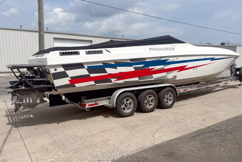 Slide: The Image of 2002 Active Thunder 37 speedboat on trailer with vibrant graphics and covered cockpit. - 2