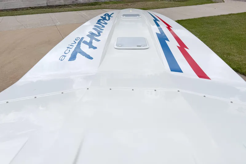 Slide: The Image of 2002 Active Thunder 37 boat hull with logo and red-blue stripes on pavement. - 32