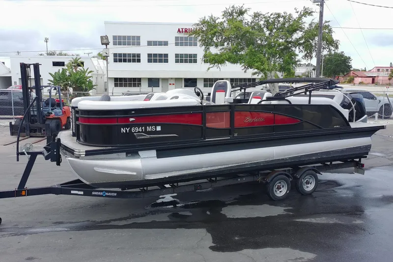 Slide: The Image of 2022 Barletta Corsa 23U pontoon boat on trailer, parked outdoors. - 3