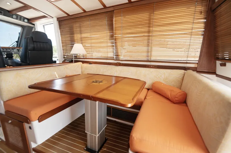 Slide: The Image of Cozy dining area in 2007 Pilot Cruiser Expedition yacht with orange seating and wooden blinds. - 17