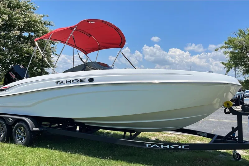 Slide: The Image of 2026 Tahoe T21 boat with red canopy on trailer, parked outdoors under blue sky. - 1