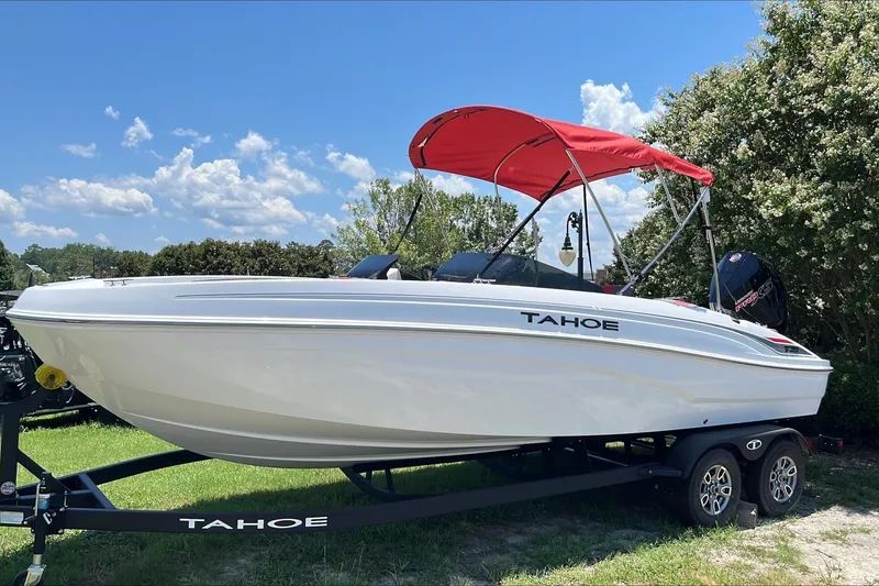 The Image of 2026 Tahoe T21 boat with red canopy on trailer, parked outdoors under blue sky. - 0