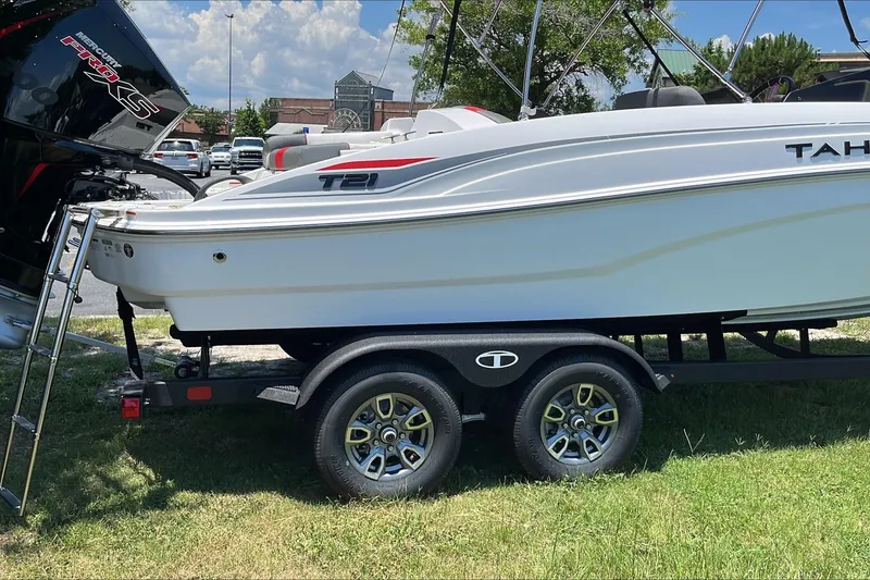 Slide: The Image of 2026 Tahoe T21 boat on trailer, parked outdoors under a sunny sky. - 2