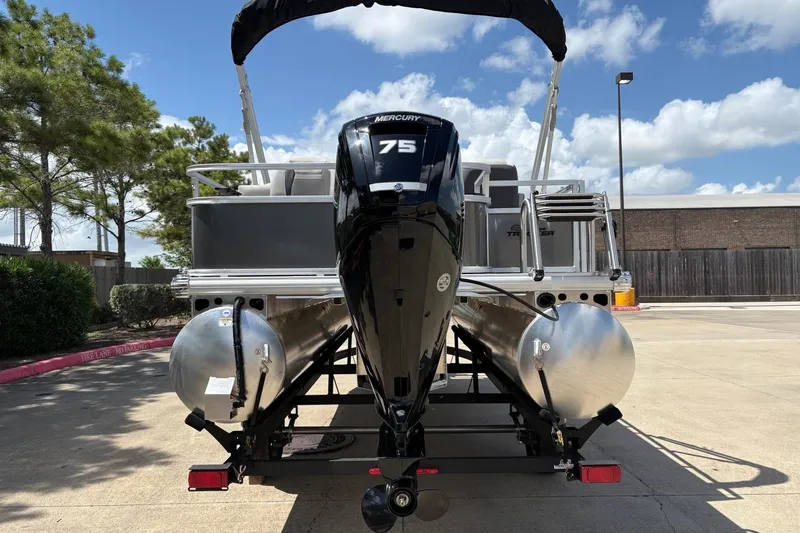Slide: The Image of 2026 Sun Tracker Bass Buggy 18 DLX pontoon boat with Mercury 75 engine, parked outdoors. - 12