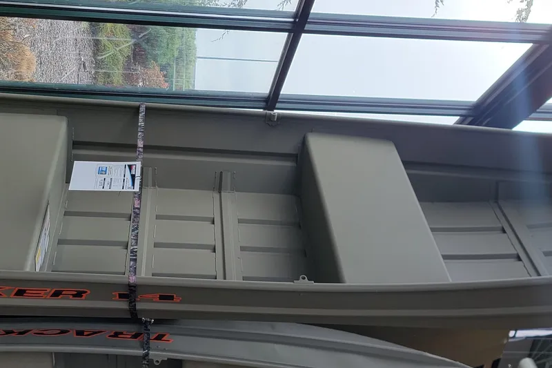 The Image of 2026 Tracker Grizzly 14 Jon boat displayed indoors with visible branding and structure. - 0
