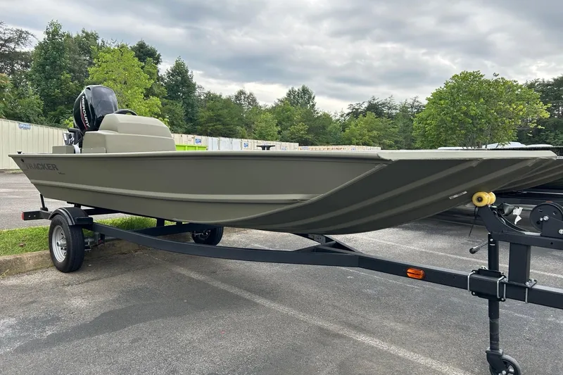 The Image of 2025 Tracker Grizzly 1648 SC boat on trailer, parked outdoors with trees in background. - 0