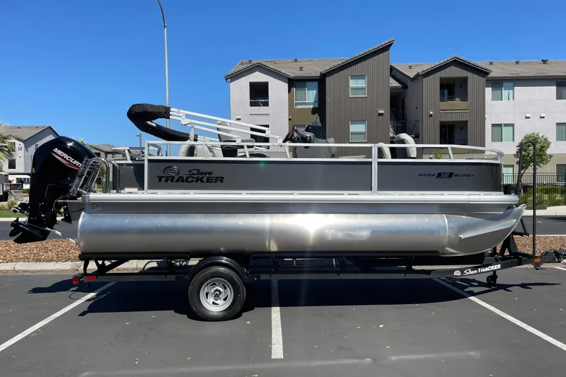 The Image of 2026 Sun Tracker Bass Buggy 18 DLX pontoon boat parked in urban setting. - 0