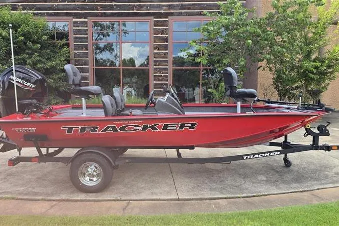 The Image of 2026 Tracker Pro Team 175 Crappie Edition boat, red, on trailer, parked outdoors. - 0