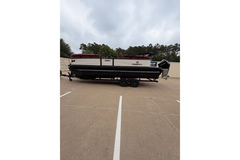 Slide: The Image of 2026 Regency 230 DL boat on trailer in parking lot, overcast sky. - 11