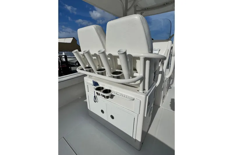 Slide: The Image of 2016 Regulator 25 boat seating with rod holders and storage under a clear blue sky. - 14