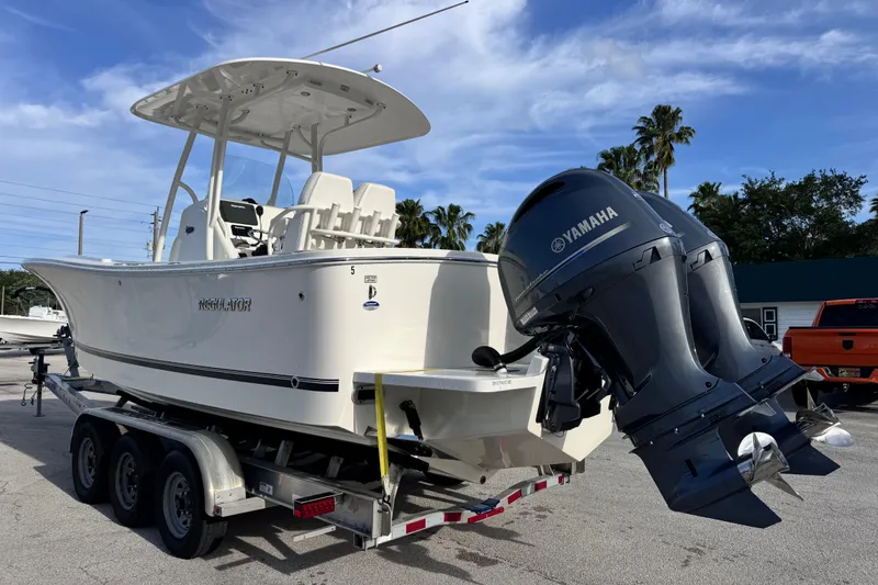 Slide: The Image of 2016 Regulator 25 boat on trailer with Yamaha engines, parked outdoors under blue sky. - 2