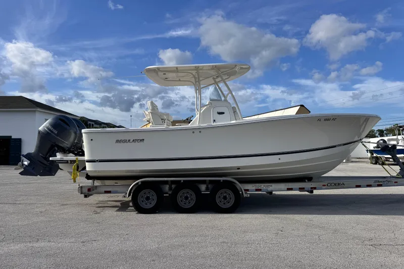 Slide: The Image of 2016 Regulator 25 boat on trailer with Yamaha outboard, parked under blue sky. - 5
