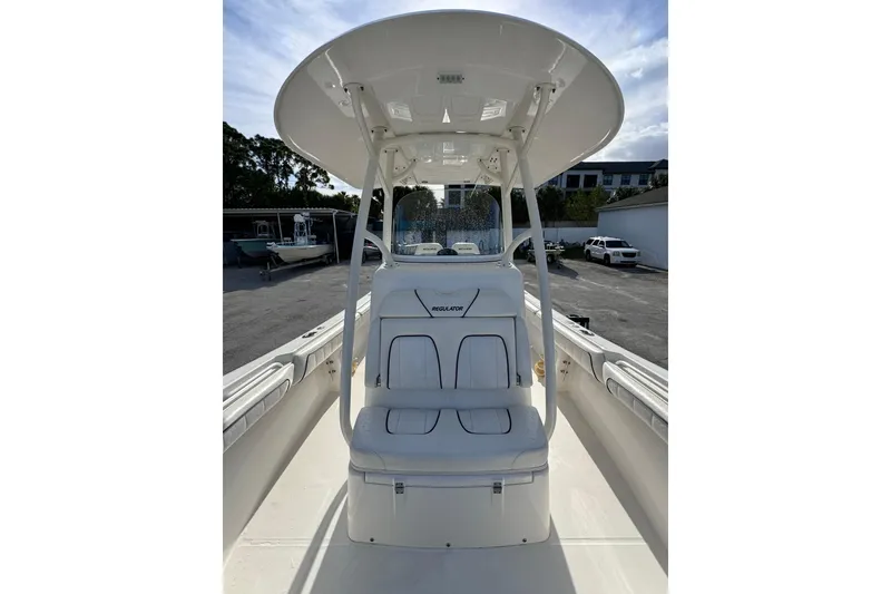 Slide: The Image of 2016 Regulator 25 boat with T-top and seating, parked outdoors. - 8