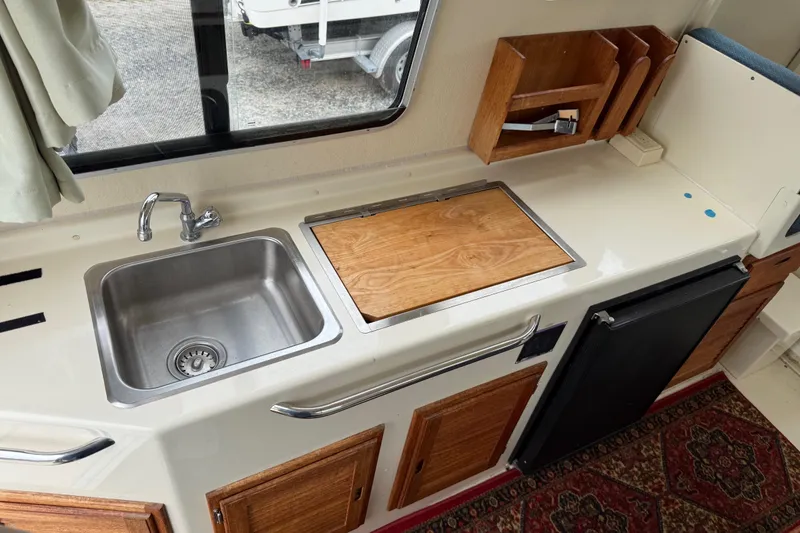 Slide: The Image of Compact kitchen area in a 2008 Rosborough RF-246 Sedan Cruiser with sink and wooden cabinetry. - 11