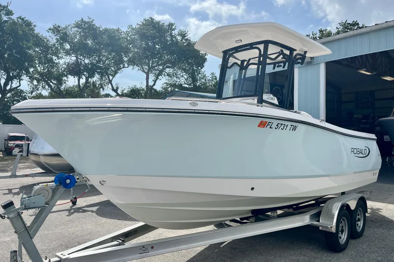 Slide: The Image of 2025 Robalo R230 Center Console on trailer outside garage. - 3