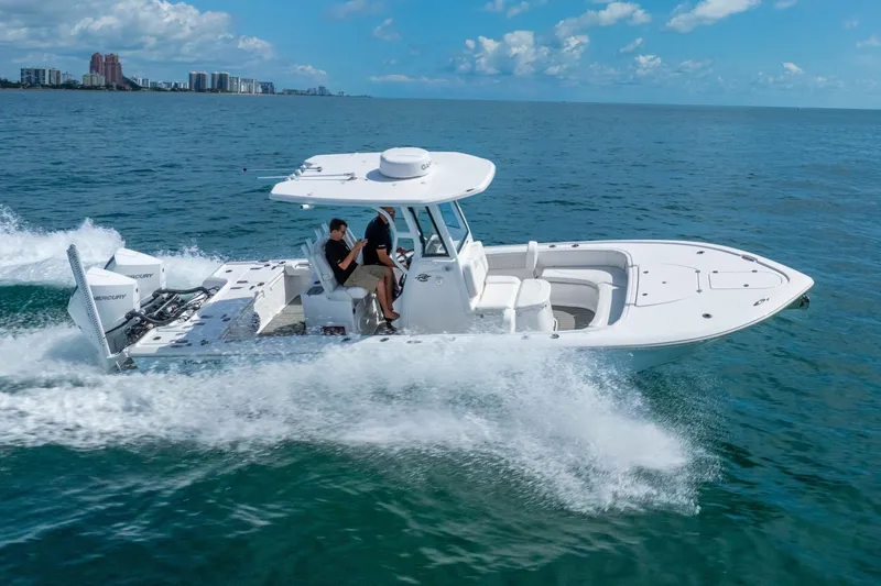 Slide: The Image of 2026 Tidewater 2700 Carolina Bay boat cruising on open water, city skyline in background. - 15