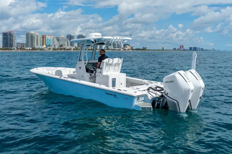 Slide: The Image of 2026 Tidewater 2700 Carolina Bay boat cruising near city skyline on a sunny day. - 2