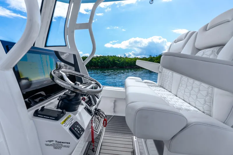 Slide: The Image of 2026 Tidewater 2700 Carolina Bay boat interior with steering wheel and seating, overlooking water. - 43