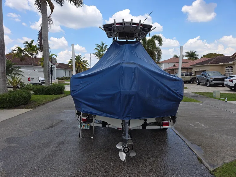 Slide: The Image of 2007 Sailfish 218 CC boat with blue cover parked in driveway. - 2