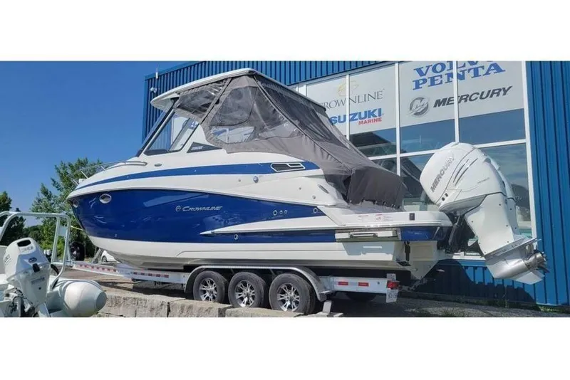 The Image of 2024 Crownline 310 CRX boat on trailer, displayed outside dealership. - 0