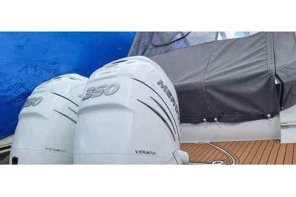 Slide: The Image of 2024 Crownline 310 CRX boat with twin Mercury Verado 350 engines, docked with blue cover. - 3