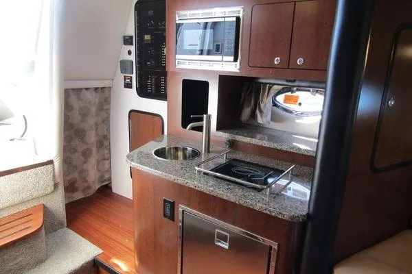 Slide: The Image of 2024 Crownline 310 CRX yacht interior with kitchenette, featuring sink, stove, and microwave. - 9