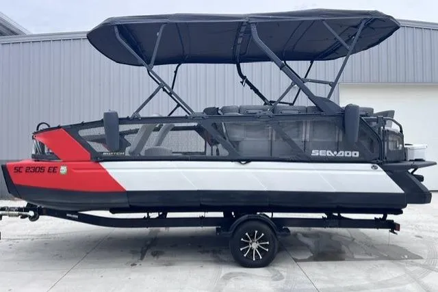 Slide: The Image of 2022 Seadoo Switch pontoon boat with canopy, parked on a trailer, side view. - 15