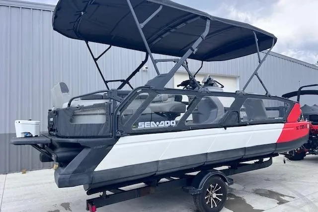 Slide: The Image of 2022 Seadoo Switch pontoon boat with canopy on a trailer, parked outdoors. - 3